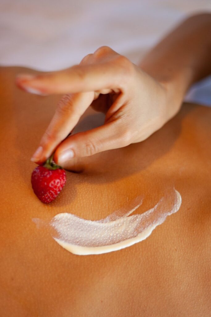 person holding red strawberry on brown wooden table